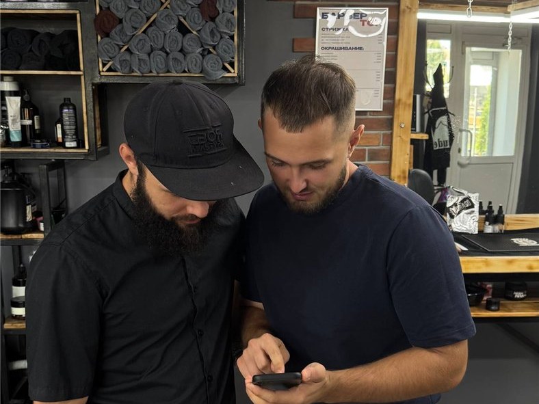 Инсаф и владелец Homie Barber смотрят в телефон